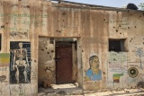 A building with bullet holes strewn across the walls.